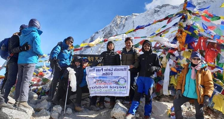 Group of hikers on a snowy mountain with prayer flags.