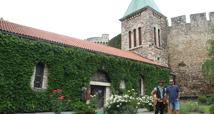 Deux hommes debout devant un bâtiment historique couvert de lierre.