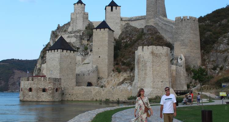 Couple se promenant près d'une forteresse médiévale au bord d'une rivière.