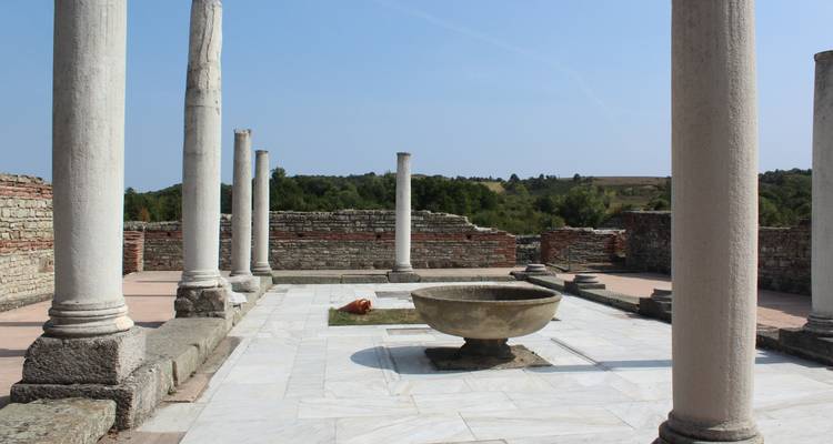 Ruines romaines antiques avec des colonnes et une fontaine.