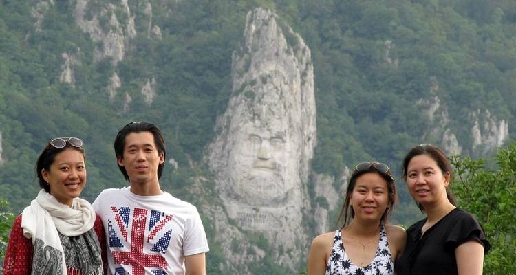 Quatre personnes posant avec un panorama montagneux présentant une paroi rocheuse sculptée.