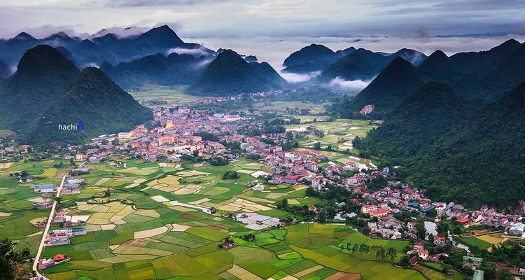 Luftaufnahme einer Stadt, umgeben von üppig grünen Bergen.