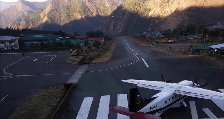 Flughafenlandebahn mit einem startbereiten Flugzeug, umgeben von Bergen.