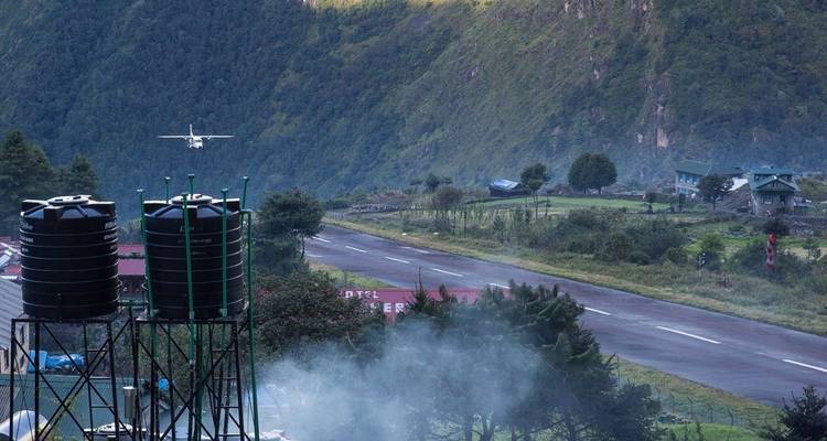 Flugzeug nähert sich einer Landebahn in einem bergigen Gebiet.