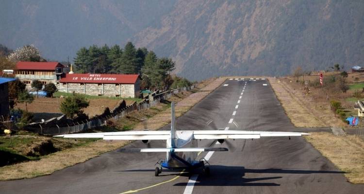Flugzeug auf einer schmalen Landebahn mit Bergblick.