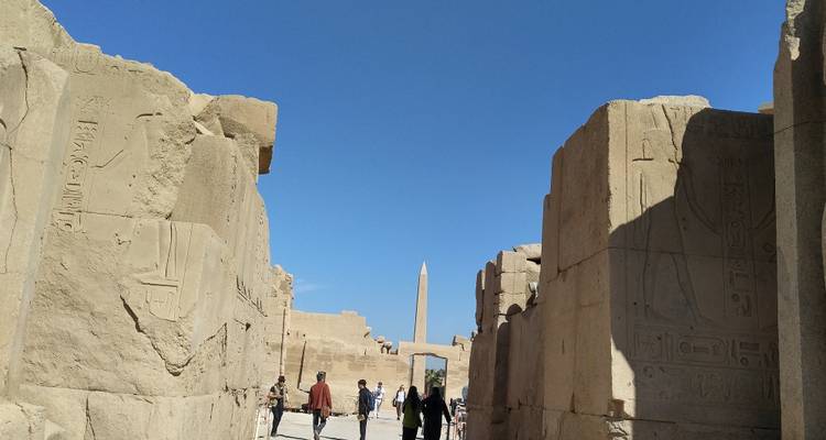 Ruinas del antiguo Egipto con jeroglíficos y turistas explorando.