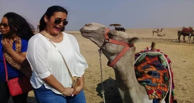 Two people with a camel in a desert setting.