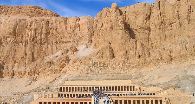 Menigten die een oude tempel bezoeken die in een rotsige klif ligt.