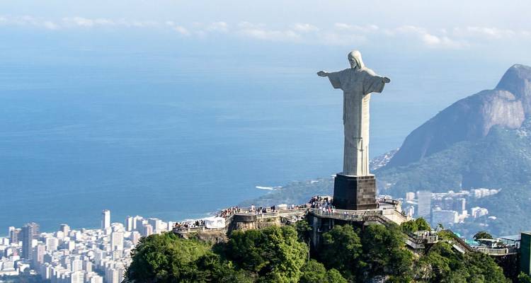 La estatua del Cristo Redentor dominando el vasto paisaje urbano y el Océano Atlántico en un día despejado.
