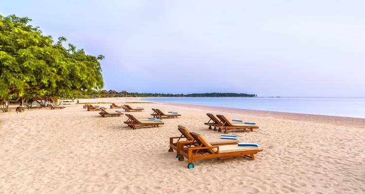 Leeg strand met ligstoelen en kalm water.