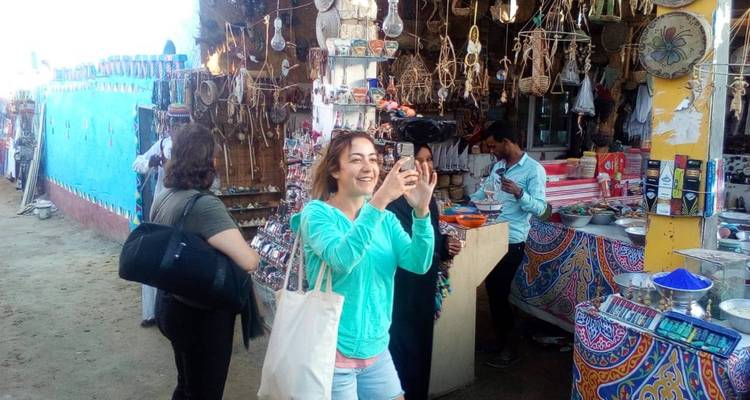 Turistas hojeando artesanías coloridas en un puesto de bazar egipcio al aire libre