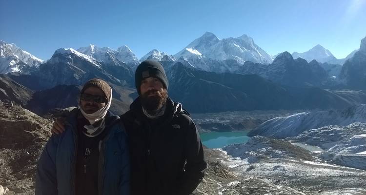 Two people posing in front of a mountainous landscape.