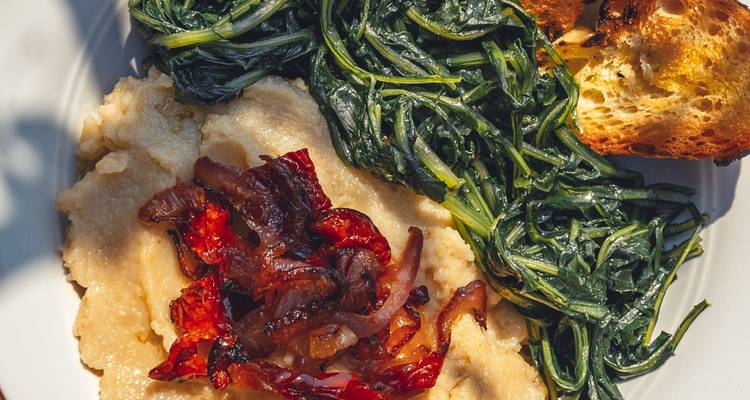Une assiette de nourriture italienne traditionnelle avec des légumes verts et du pain.