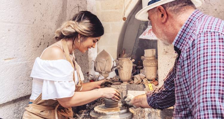 Une femme et un artisan engagés dans la fabrication de poterie dans un cadre pittoresque.