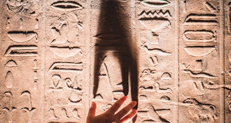 Nahaufnahme von Hieroglyphen mit einer Hand im Licht.