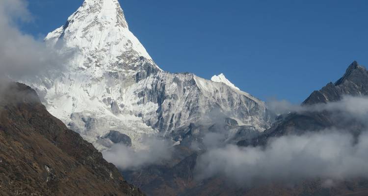 Blick auf einen majestätischen schneebedeckten Berggipfel, umgeben von Wolken.