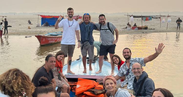 Un grupo de turistas alegres navega en una pequeña barca por el río Ganges al amanecer.
