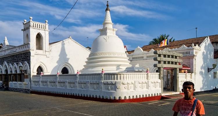 Witte tempel met een stupa en mensen die voorbijlopen.