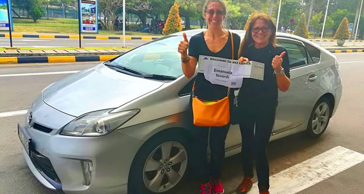 Twee vrouwen poseren met een auto die op straat geparkeerd staat.