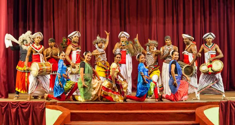 Kleurrijke culturele voorstelling met dansers in traditionele kledij op het podium.