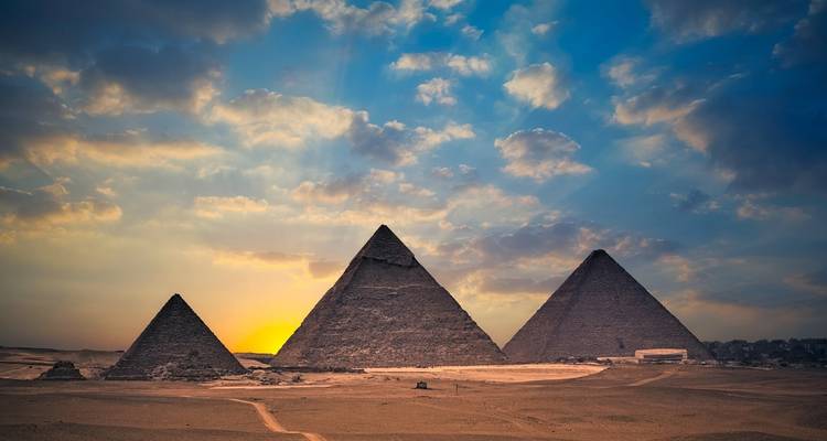 Pyramids of Giza with a sunset in the background.