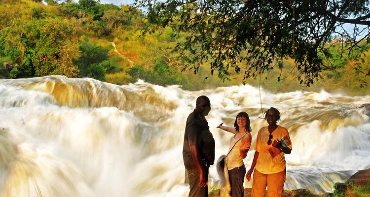 Groupe de touristes posant devant une cascade.