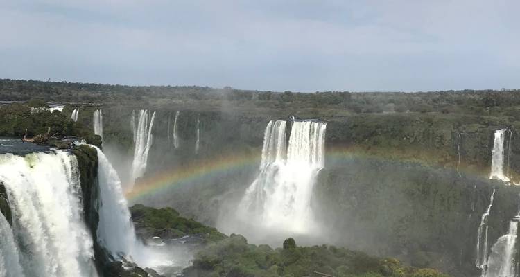 Waterfalls cascading down with a rainbow over the mist.