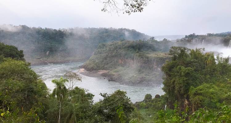River view with misty jungle and distant waterfalls.