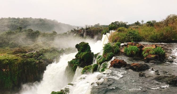 Top view of waterfalls flowing into misty surroundings.