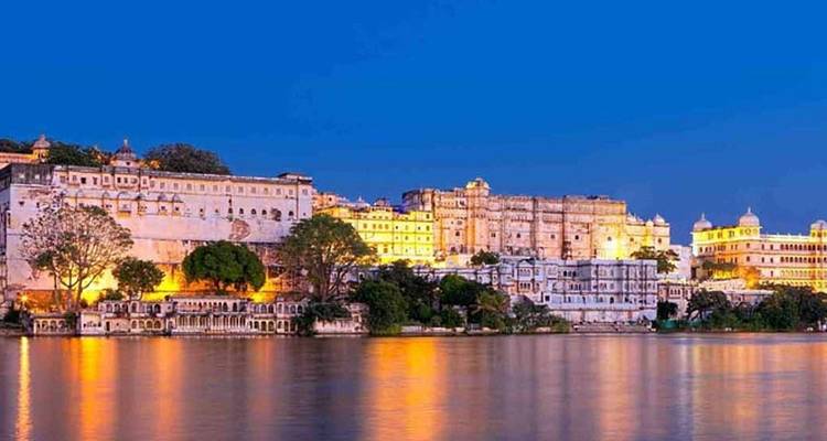 Cityscape of Udaipur with illuminated palaces by the lake.