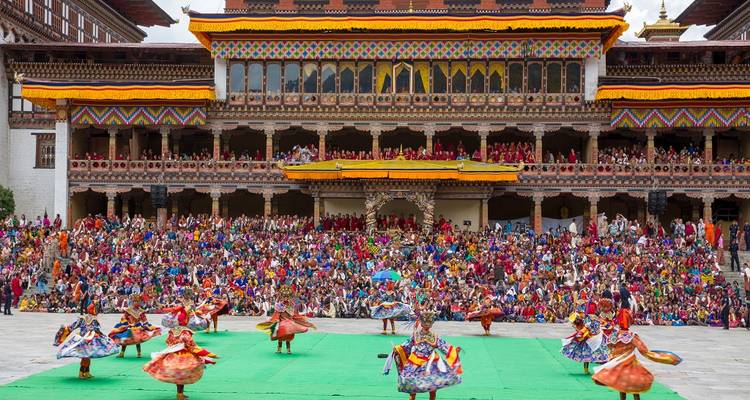 Feestelijke optocht met dansers voor een traditioneel gebouw.