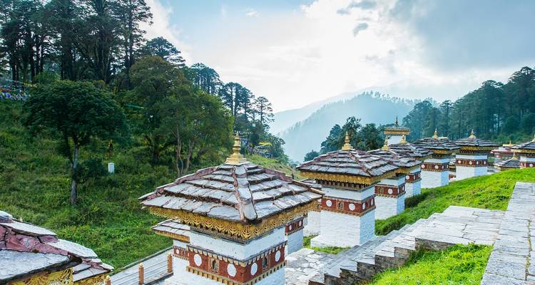 Chortens op een heuvel met mistige bergen op de achtergrond.