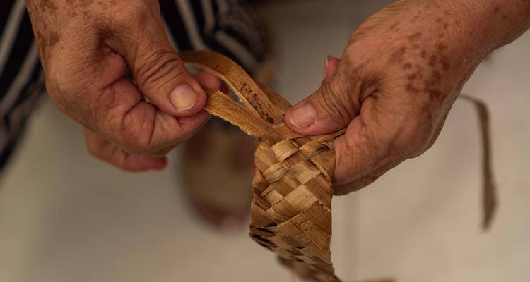 Gros plan sur des mains tressant un panier.