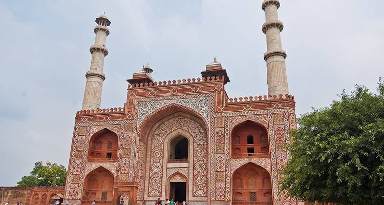 Large ornate gate of a red sandstone building with people.