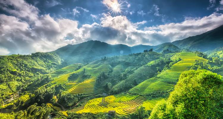 Sonne scheint über Terrassenfelder und Berge.