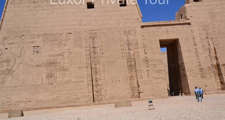 Dos personas caminando hacia un antiguo templo egipcio.