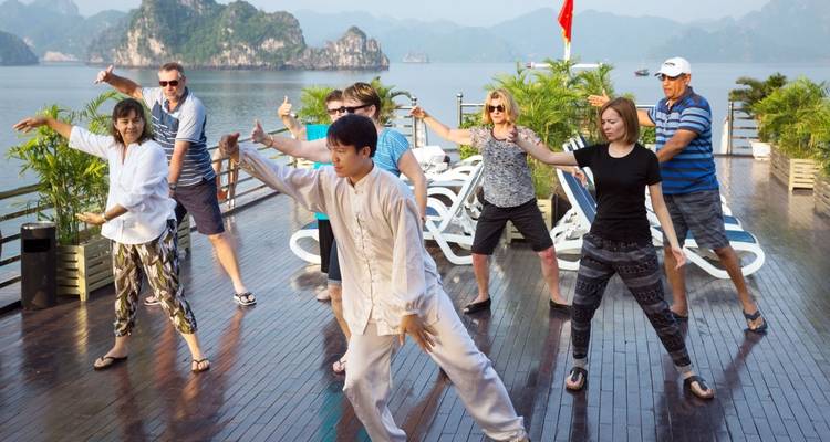 Tai Chi-Stunde auf einem Kreuzfahrtdeck mit der malerischen Halong-Bucht im Hintergrund.