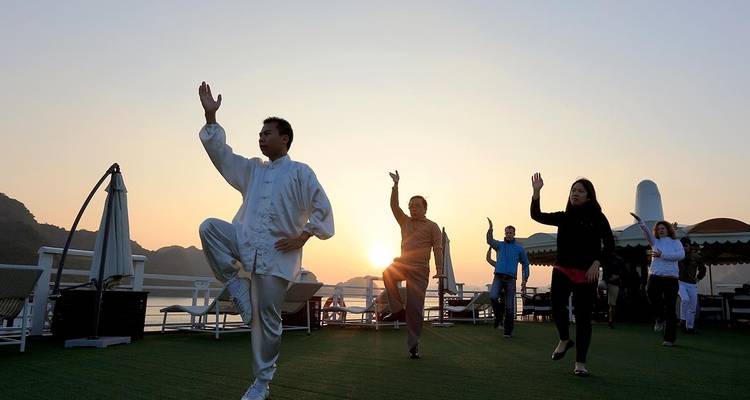 People practicing Tai Chi on a cruise deck at sunrise.