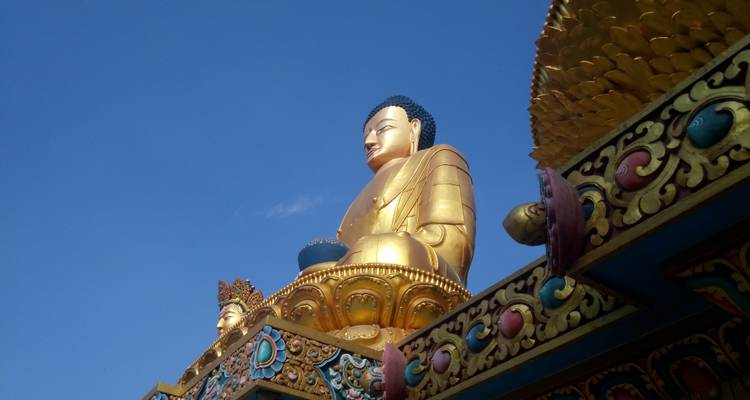 Eine große goldene Buddha-Statue vor einem klaren blauen Himmel.