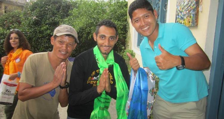 Gruppe von Menschen, die sich mit traditionellen Schals begrüßen und für ein Foto posieren.