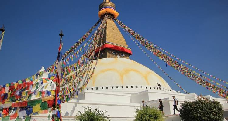 Grote stupa met gebedsvlaggen tegen een blauwe hemel.