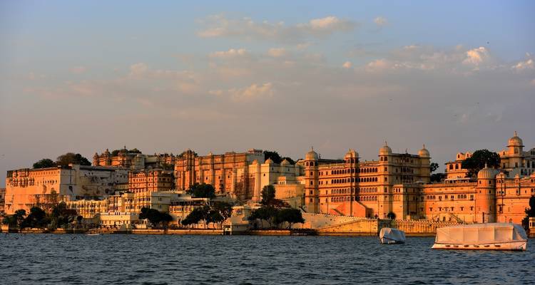 Historic palatial buildings by a lake with a boat in the foreground.
