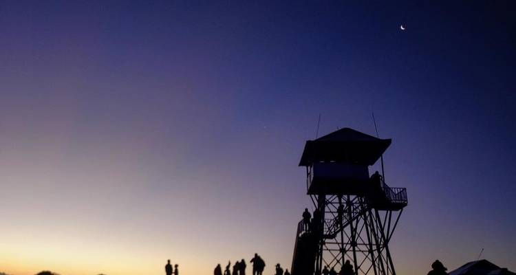 Silhouette de personnes sur une tour d'observation à l'aube.