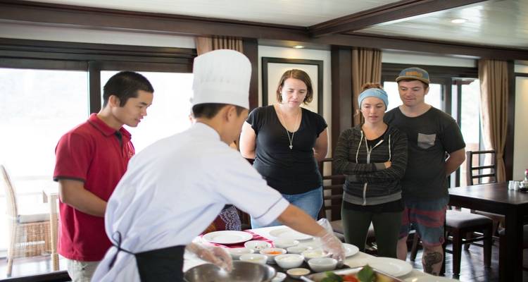 Cooking class on a boat with a chef instructing tourists.