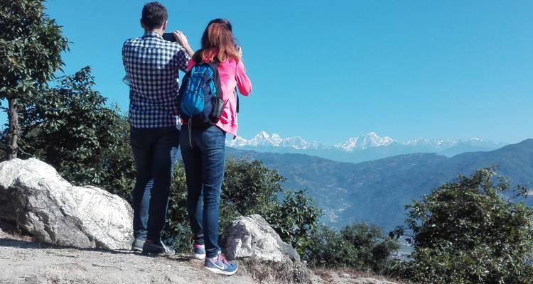Zwei Personen fotografieren entfernte schneebedeckte Berge.