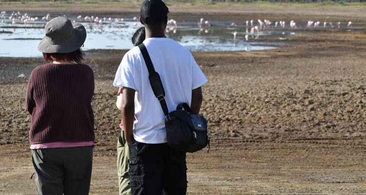 Individuen die een meer observeren met flamingo's in de verte.