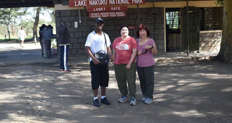 Drie mensen poseren voor de ingang van Nationaal Park Lake Nakuru.