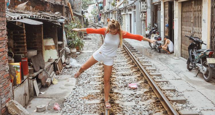 Person balancing on railway tracks in an urban area.