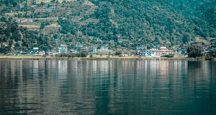 Reflection of buildings and tree-lined hills on the water.