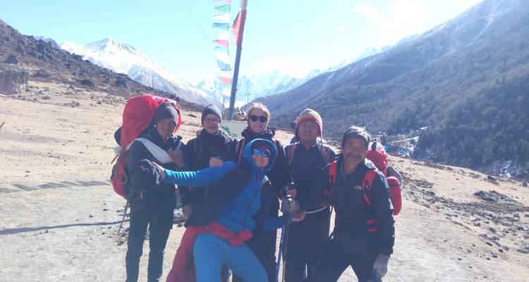 Group of trekkers smiling with a mountainous backdrop.